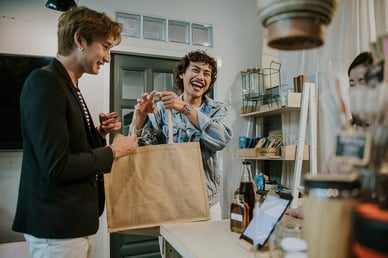 Two shoppers smiling after making a purchase at a small business. 