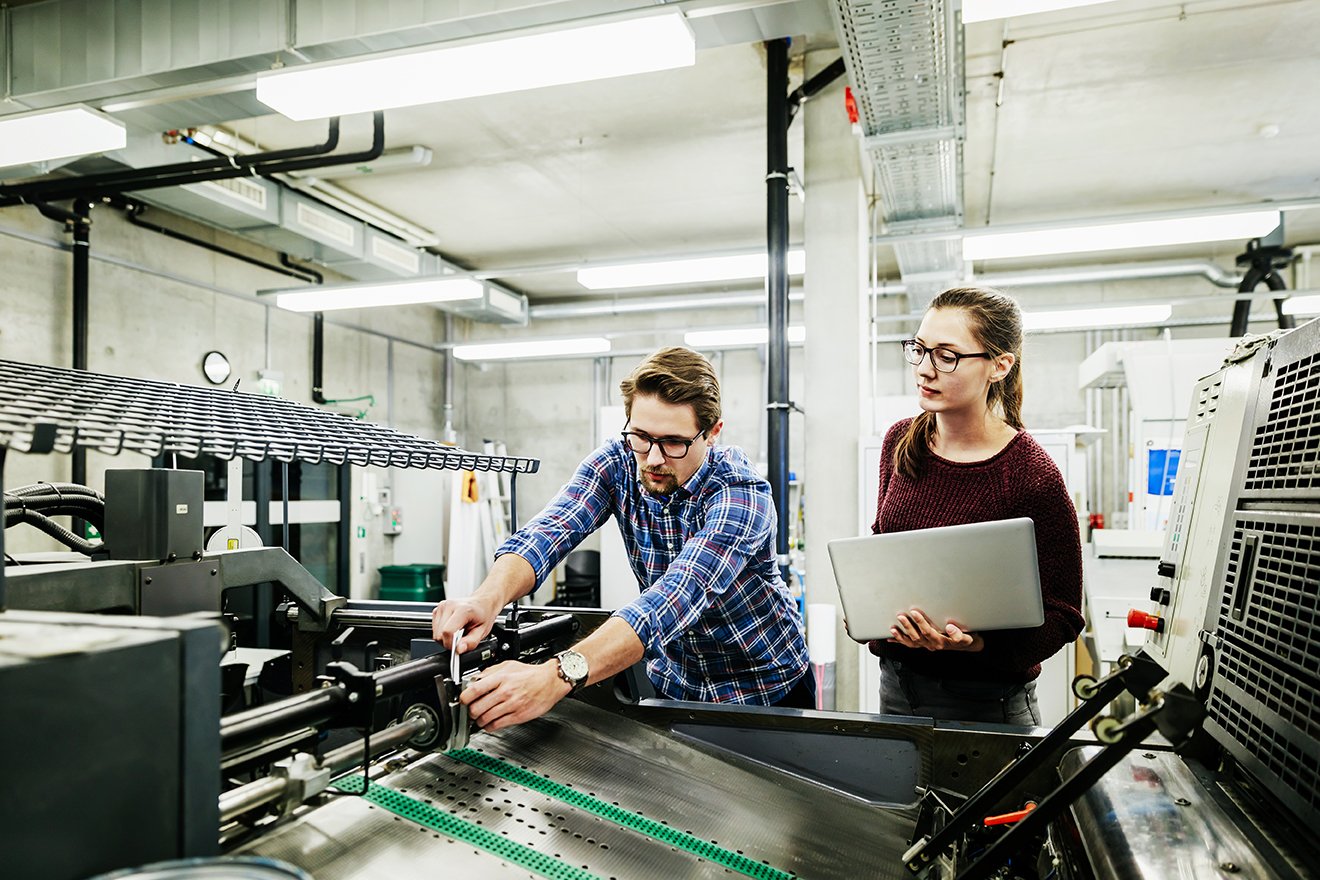 One male student and one female student working on a machine at a university.