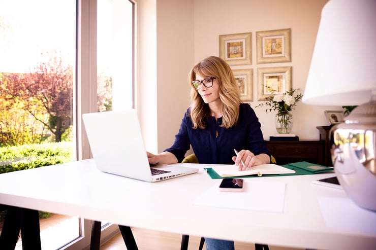 Une femme assise dans un bureau à domicile et regardant un ordinateur.